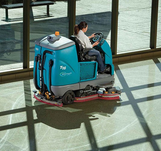 Uma lavadora de condutor sentado, alimentada a bateria T16, a limpar o pavimento de um aeroporto.